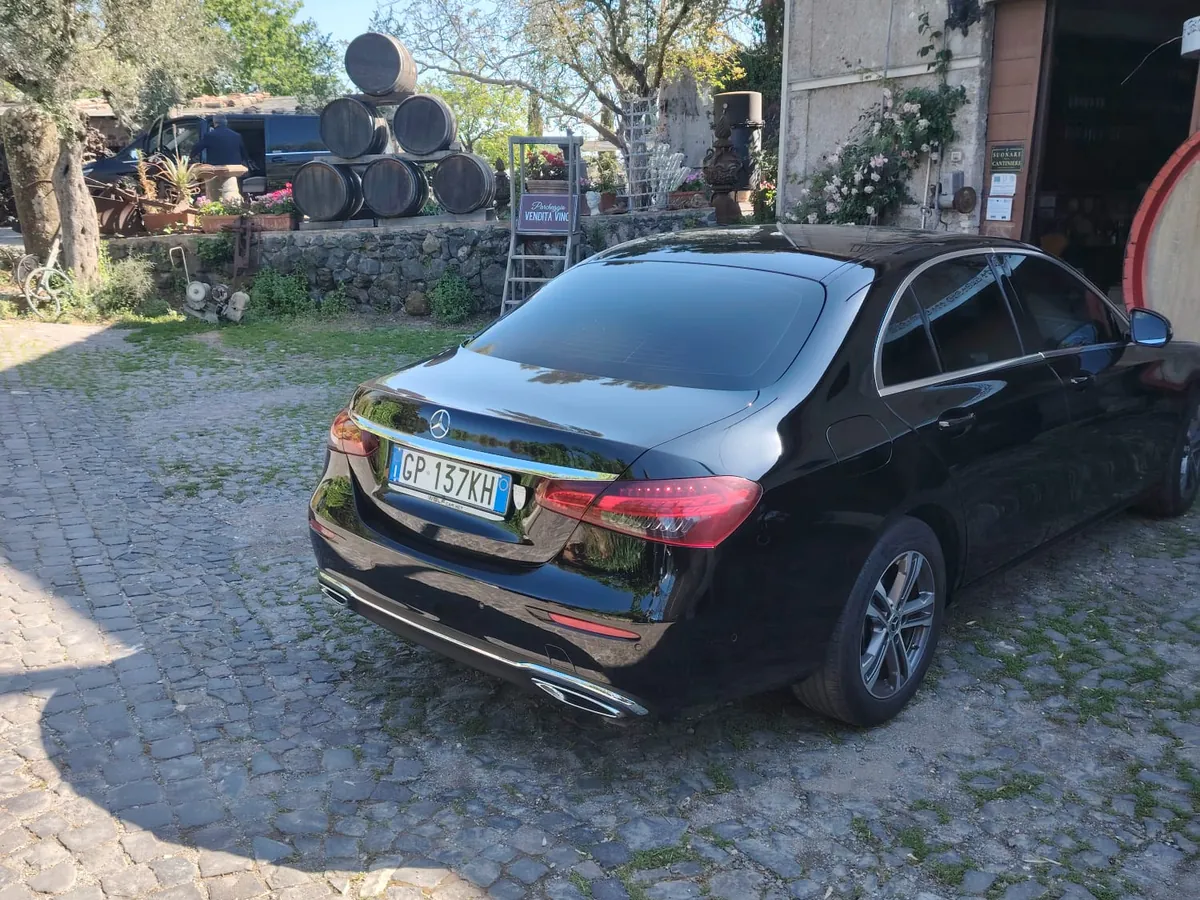 La Mercedes Classe E nera di Luxury Travel Agency vista da dietro, sul selciato del cortile di una cantina